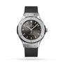 The Hublot Classic Fusion Racing Grey Titanium features a titanium case, grey dial, black rubber strap, metallic hour markers on white, and a date display at 3 oclock.