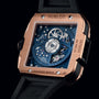 Close-up of the Hublot Square Bang Unico King Gold Blue Ceramic, showcasing its King Gold case, exposed mechanical movement with blue inner plate and inscriptions, paired with a black rubber strap.