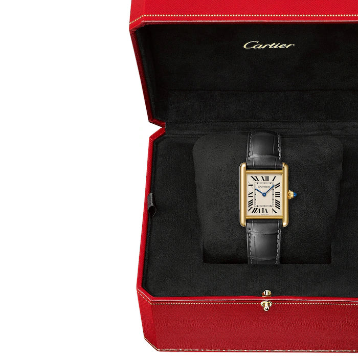 The Cartier Tank Louis Medium Model features a rectangular gold case, white dial with black Roman numerals, blue hands, and black leather strap, presented in an open red Cartier box with black velvet interior—reflecting Louis Cartier's legacy.