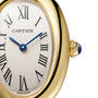 Close-up of a gold Cartier Baignoire watch with blue hands, Roman numerals, and a sapphire crown.