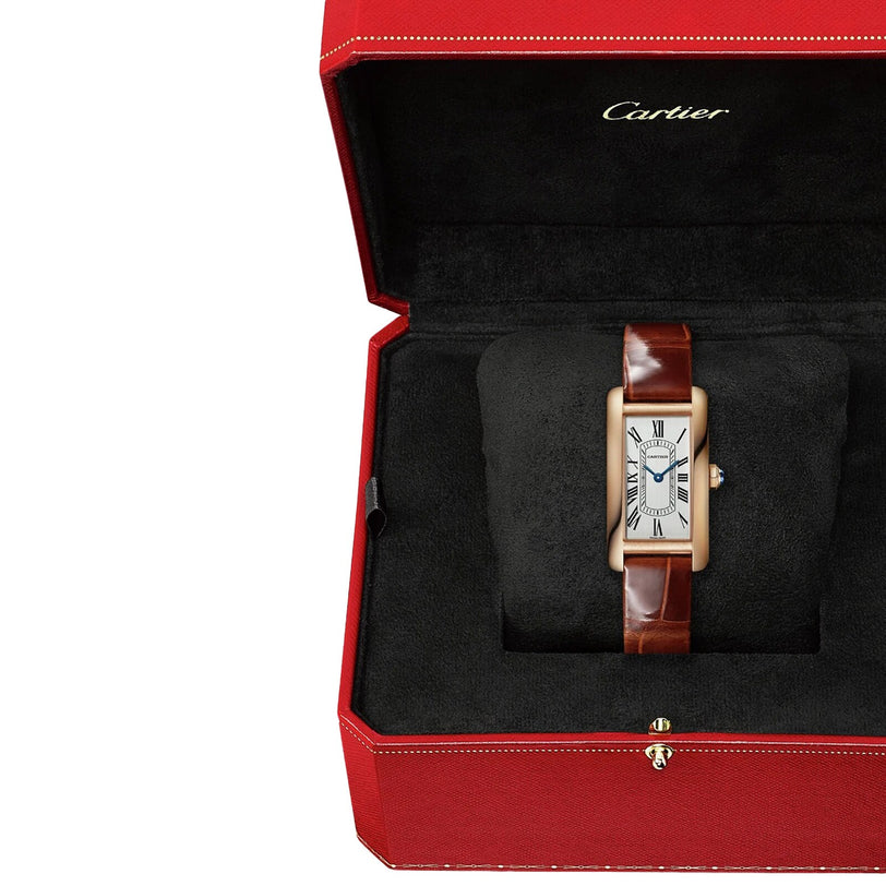 A Cartier Tank Américaine wristwatch is shown in an open red Cartier box with a black interior.