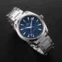 An OMEGA Seamaster Aqua Terra 150M wristwatch with a blue dial, silver hour markers, and stainless steel bracelet is shown on a black surface.