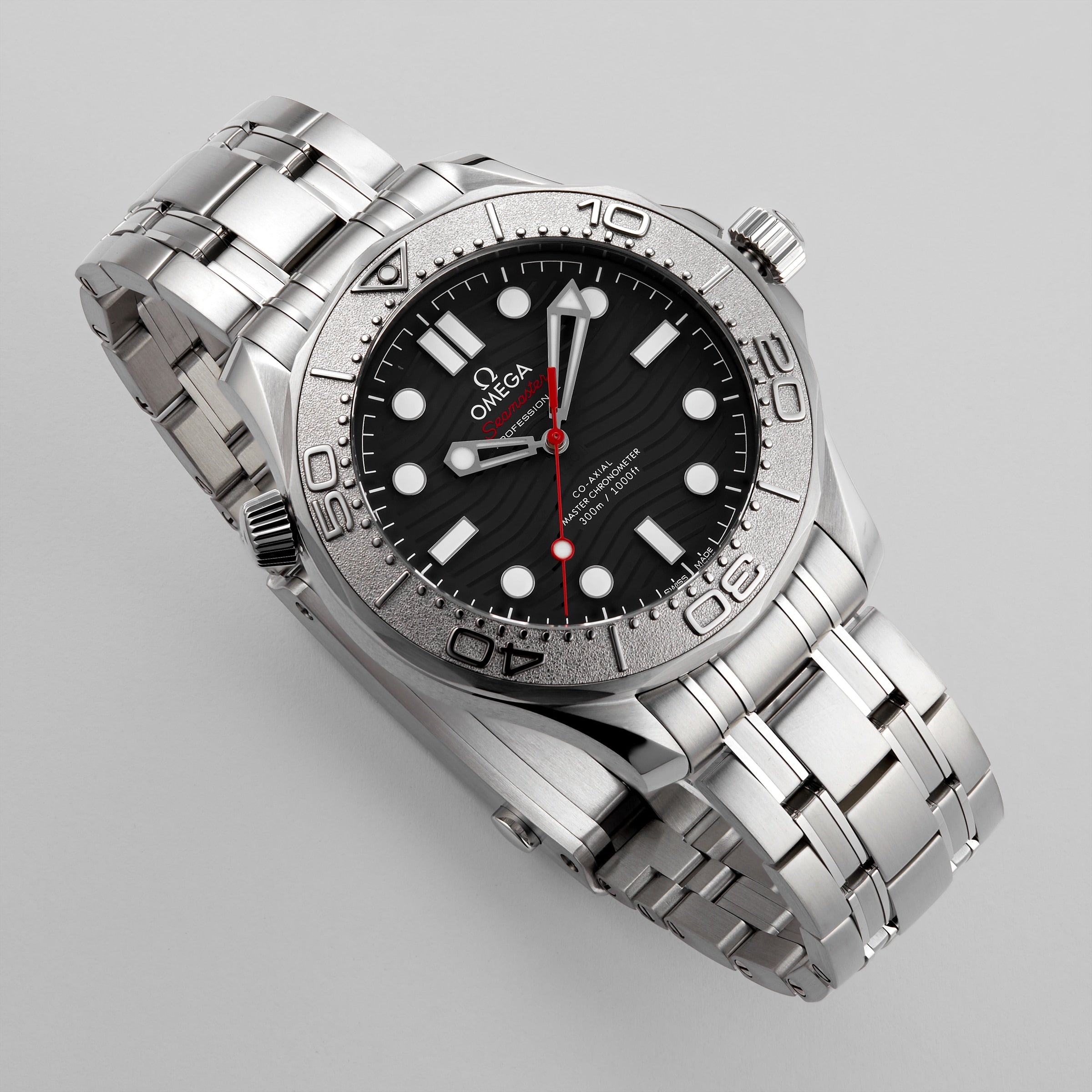 An OMEGA Seamaster Diver 300M Nekton Edition in stainless steel with a black, wave-pattern ceramic dial, white markers, red second hand, and metal bracelet shown on a light gray background.