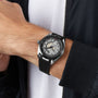 A person in a black jacket and white shirt wears the OMEGA Seamaster Aqua Terra 150M, featuring a silver and black wristwatch with a detailed, partially exposed mechanical dial in a sleek titanium case.