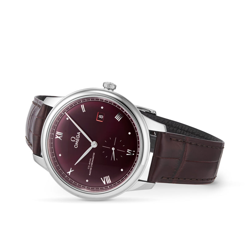 The OMEGA De Ville Prestige features a burgundy dial with silver Roman numerals, date window at 3 o’clock, brown leather strap, and is powered by the Master Co-Axial Calibre 8802 movement.