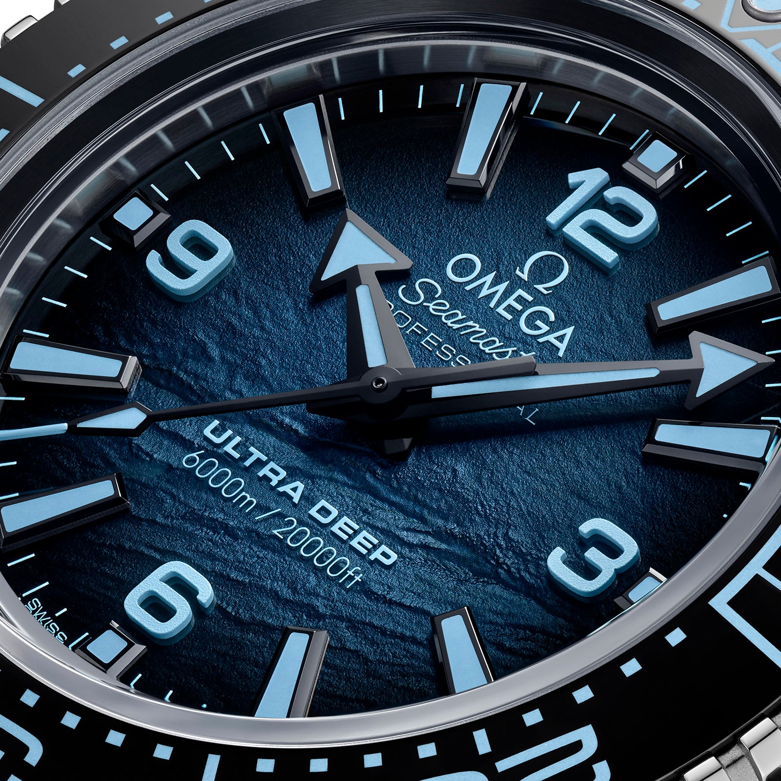 Close-up of the OMEGA Seamaster Planet Ocean 6000M watch face, featuring blue hands, numerals, and 6000m/20000ft on a textured blue background—an icon among saturation divers’ timepieces.