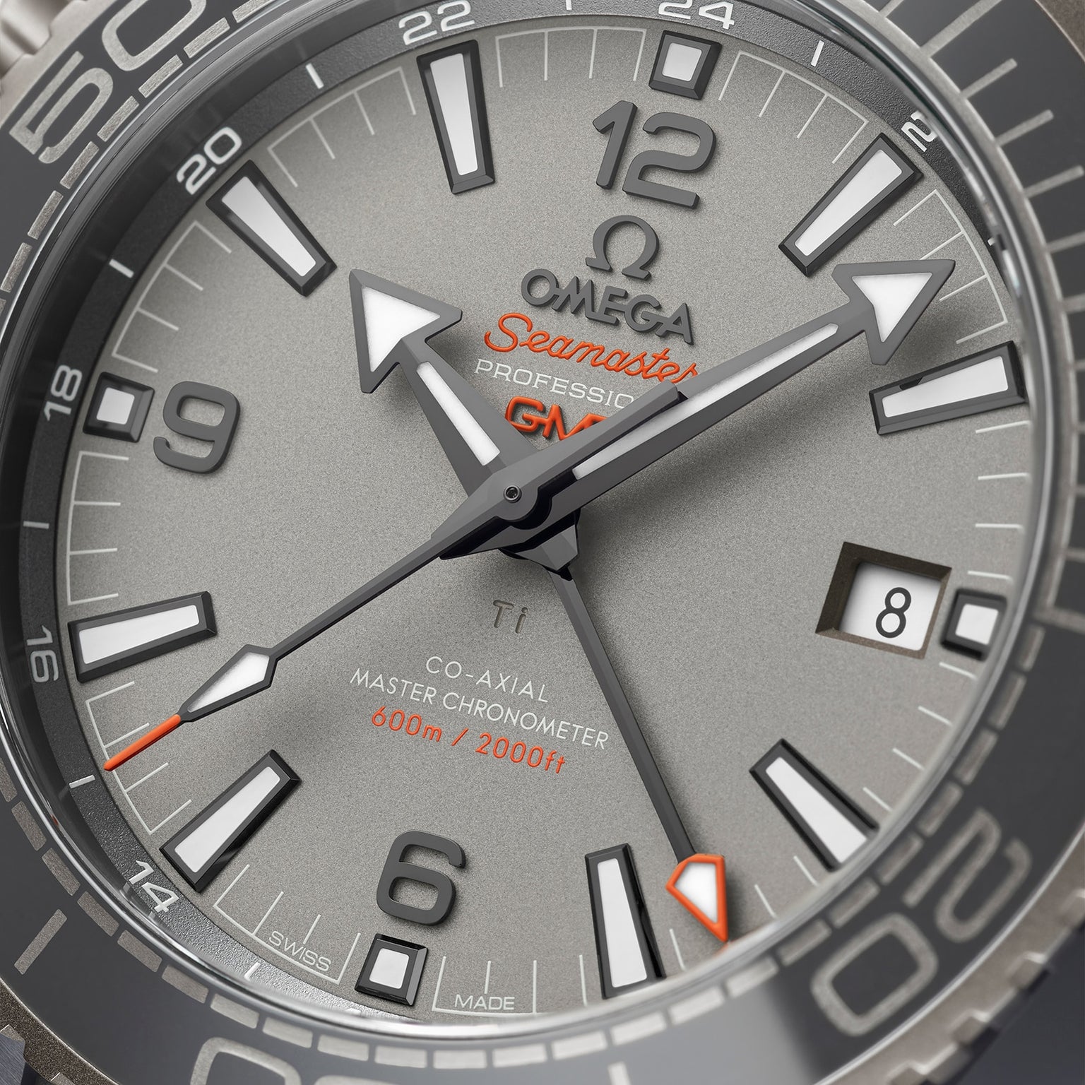 Close-up of an OMEGA Seamaster Planet Ocean 600M watch face at 10:08 with the date set to the 8th, displaying a gray dial, bold markers, orange accents, and certified Master Chronometer precision.