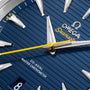 Close-up of the OMEGA Seamaster Aqua Terra 150M watch face, featuring a blue textured dial, silver hour markers, yellow second hand, date at 8 o’clock, and powered by the Co-Axial Master Chronometer Calibre 8900 in stainless steel.
