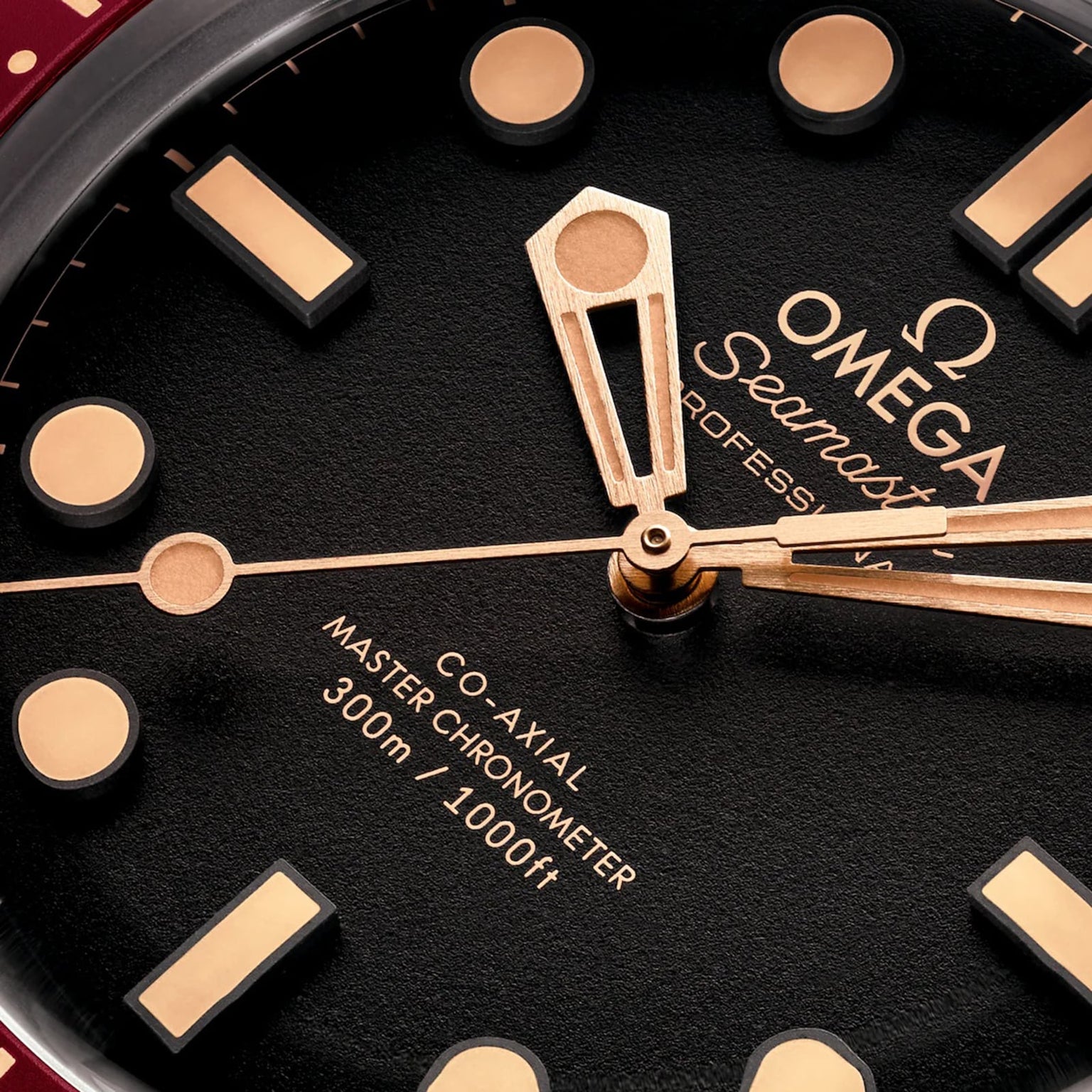 Close-up of the OMEGA Seamaster Diver 300M watch face in Bronze Gold, showing gold hands, hour markers, and OMEGA Co-Axial Master Chronometer 300m / 1000ft text.