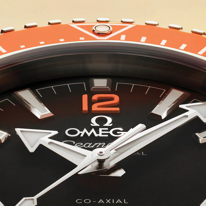 Close-up of an Omega watch with a black face and orange accents.