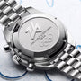 Close-up of a silver watch with 'Milano Cortina' branding on a light blue background