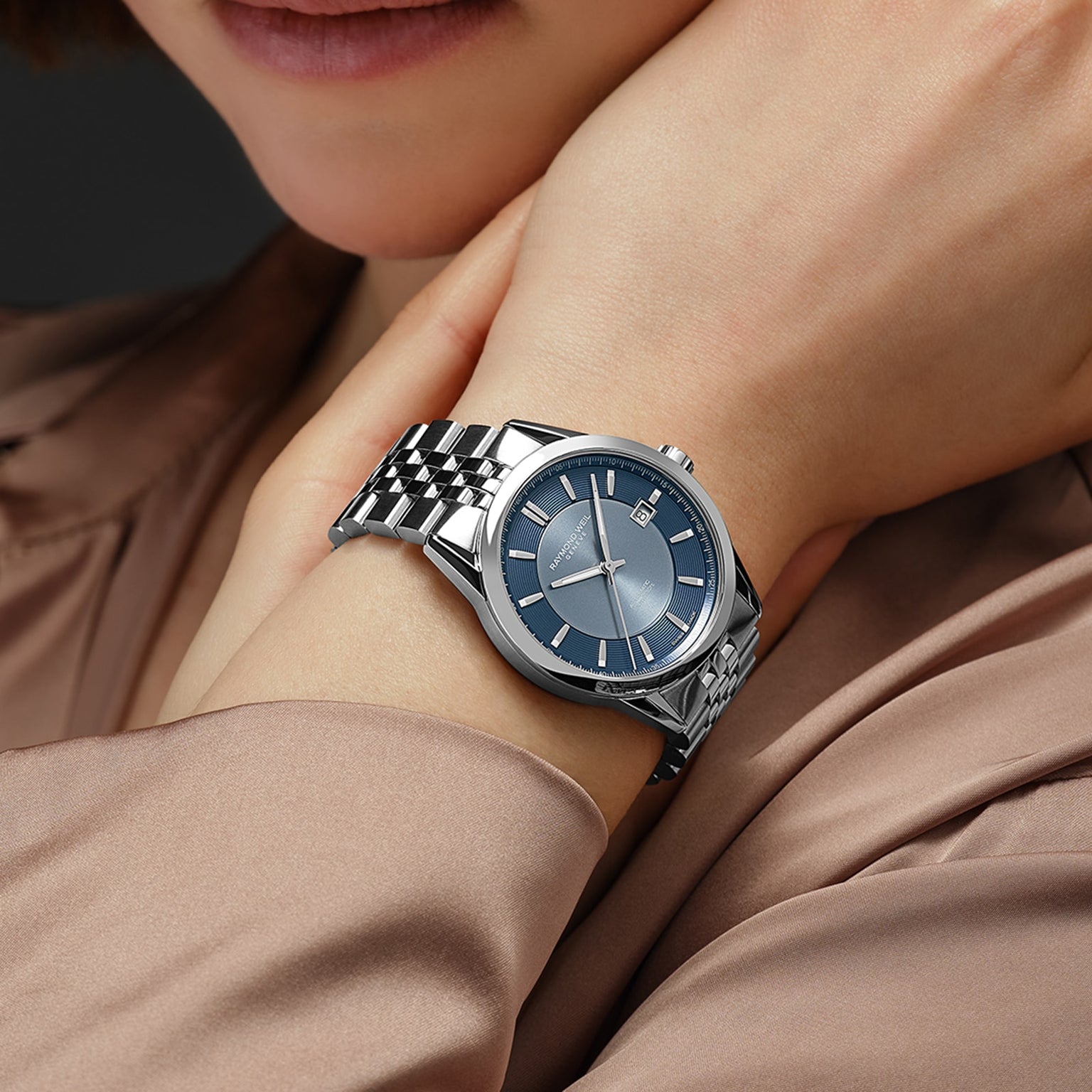 A person wearing a Raymond Weil Freelancer Automatic Blue Dial watch with a sunrayed blue dial and metal band, resting their hand on their neck.