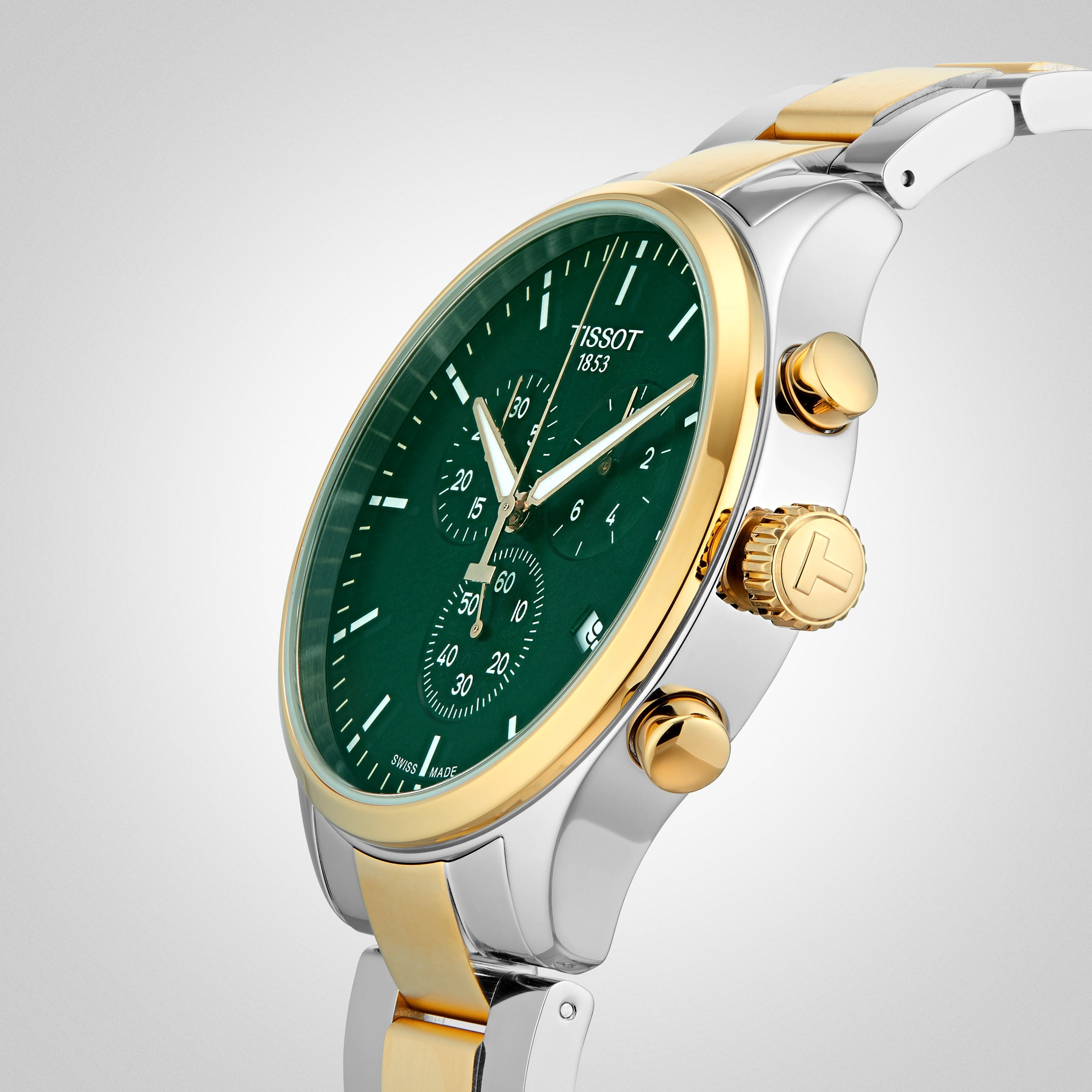 A Tissot Chrono XL Classic wristwatch with a green dial, gold and silver metal band, gold pushers and crown, and stainless steel case is displayed against a light background.