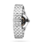 The Tissot Classic Dream Swissmatic is a silver metal watch with a linked bracelet, featuring an exhibition case back that reveals the inner mechanism.