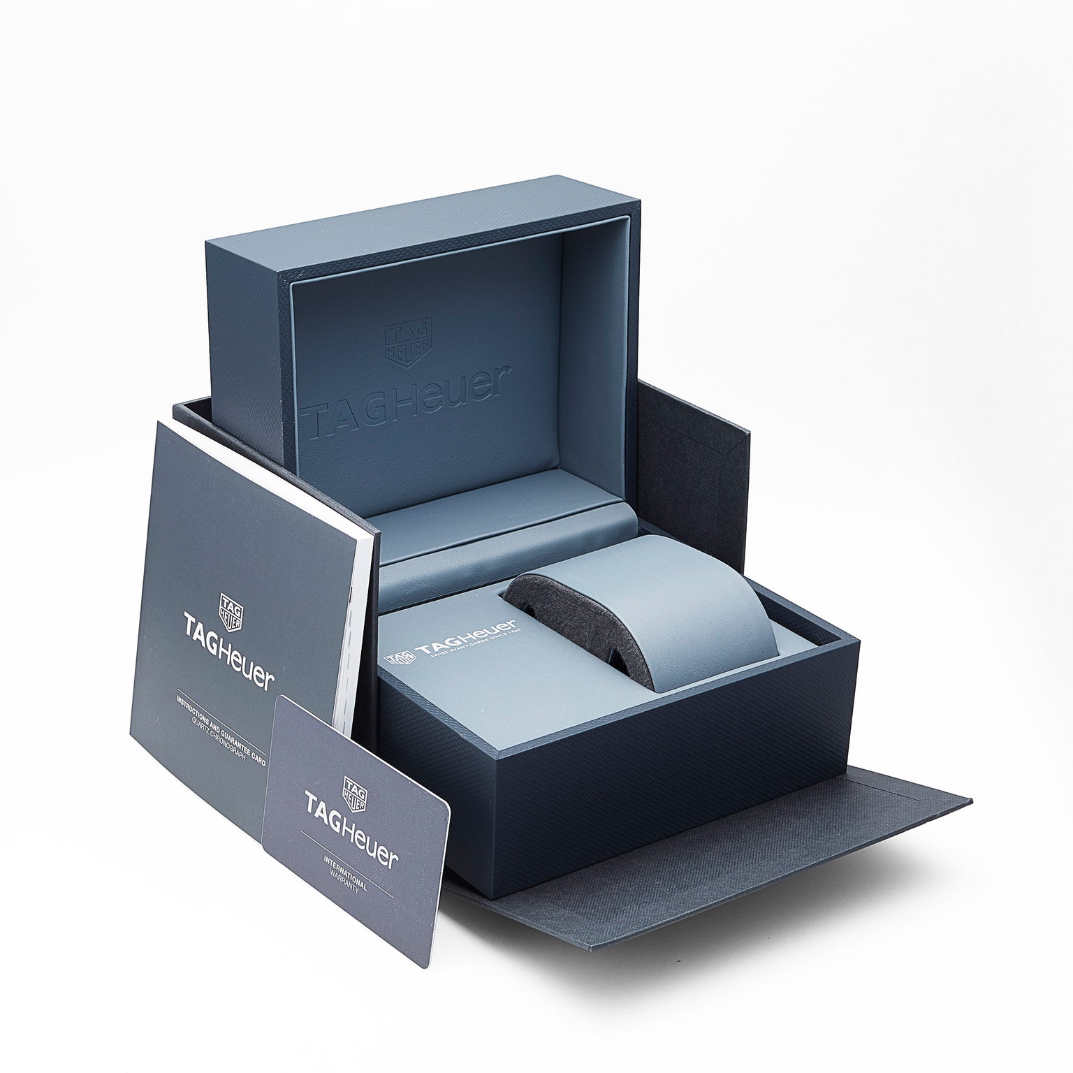 A TAG Heuer watch box is open, showing interior packaging and cards without the watch. Booklets and a card are displayed beside it, highlighting the iconic TAG Heuer Special Edition Formula 1 Date design.