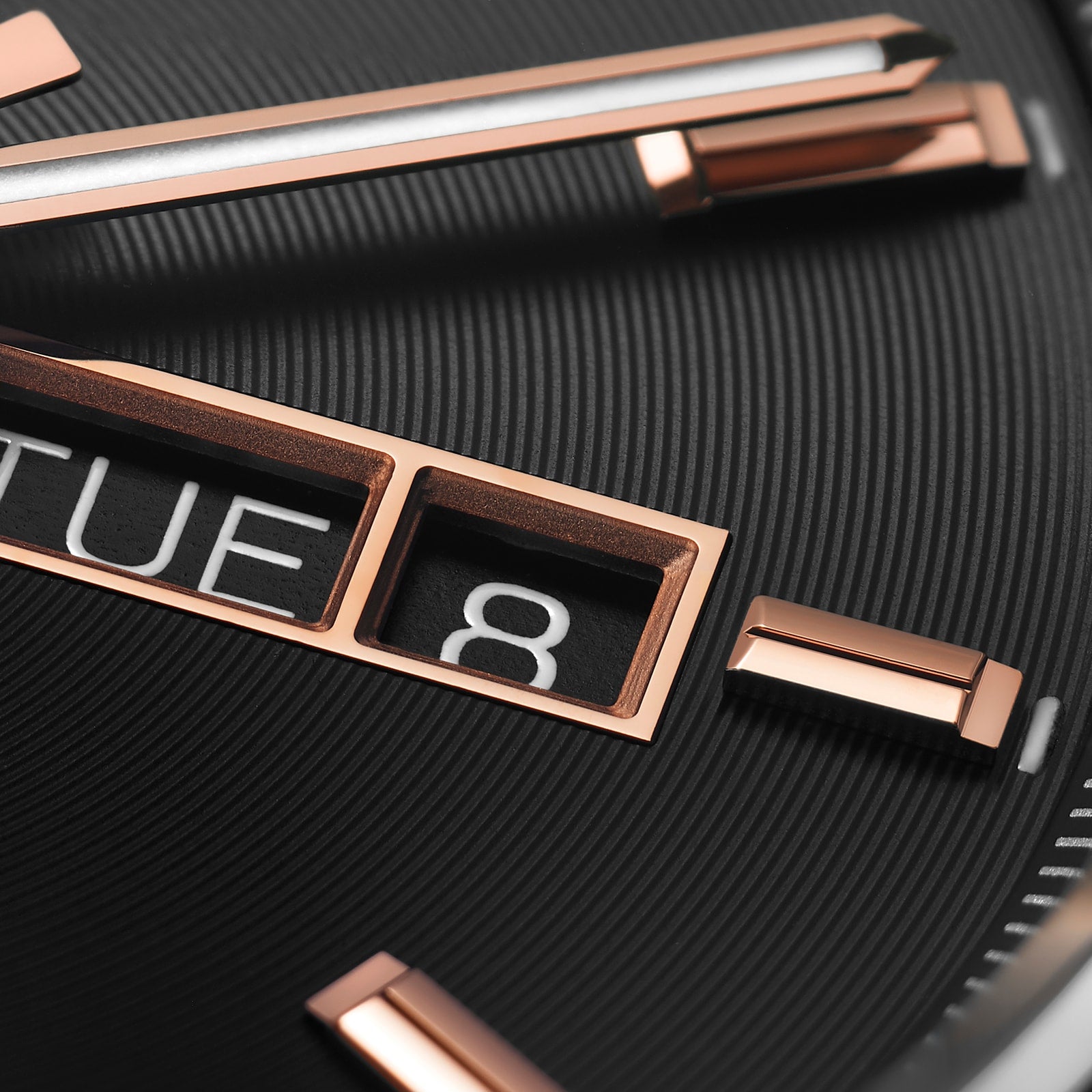 Close-up of the TAG Heuer Carrera Day-Date watch face in black with rose gold hands and markers, featuring calibre 5 automatic movement and separate day/date windows—a true symbol of endurance.