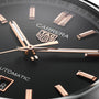 Close-up of the TAG Heuer Carrera Date watch face, featuring rose gold hour markers and hands in a sleek steel case, with Automatic labeling and part of the date window visible.