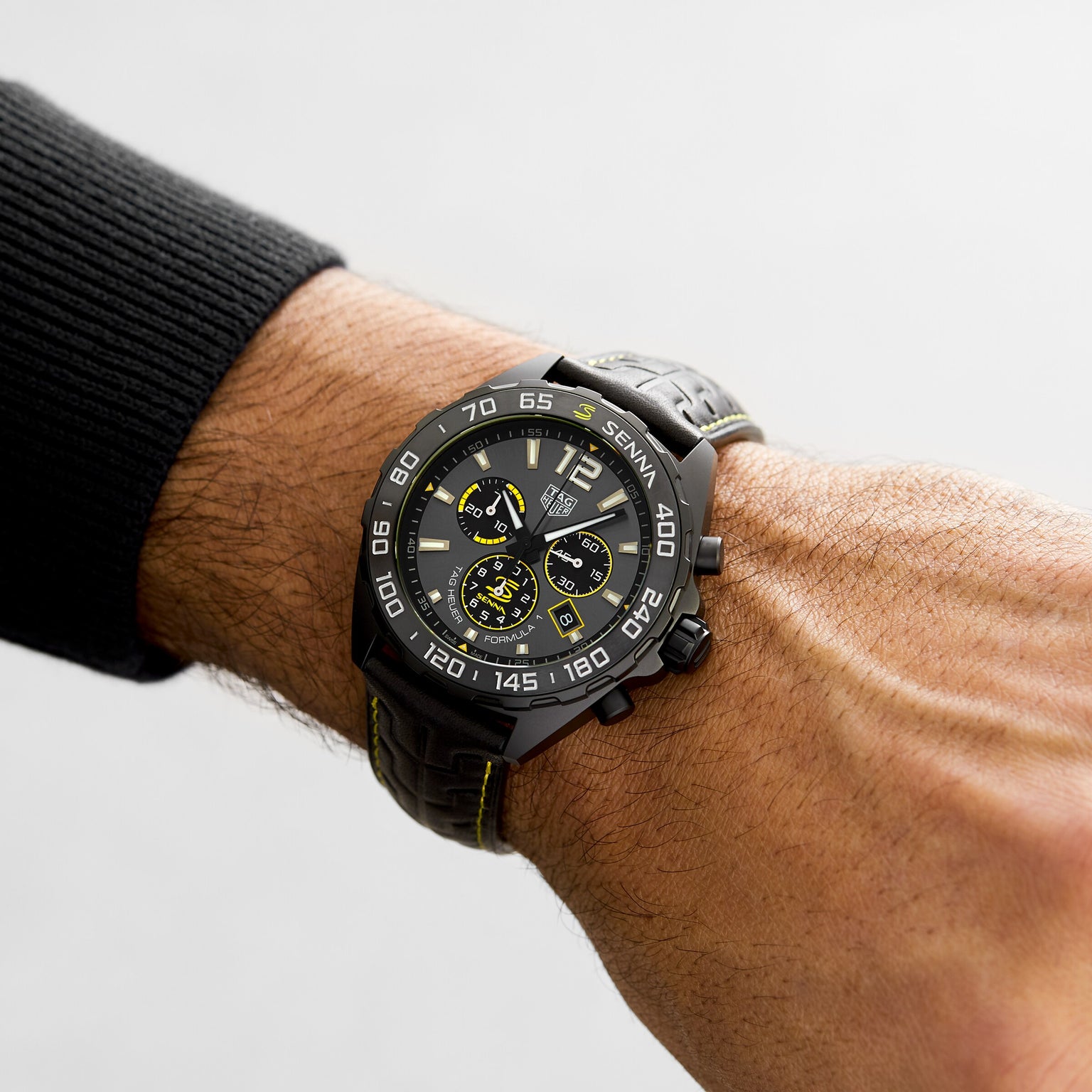 A close-up of a wrist wearing the TAG Heuer Special Edition Formula 1 Senna watch, featuring yellow accents and a black strap.