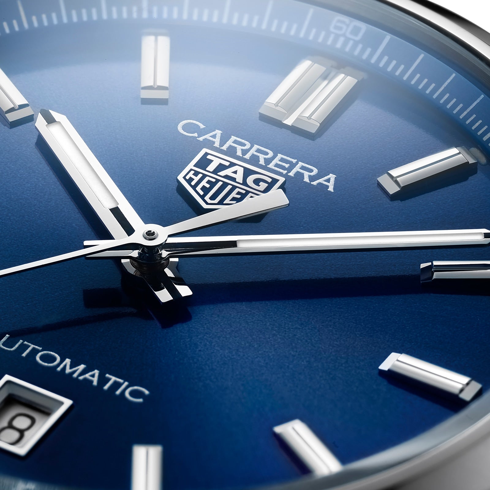 Close-up of the TAG Heuer Carrera Date watch face in blue, featuring silver hour markers, hands, and a date window. This timepiece is powered by an automatic movement for lasting performance.