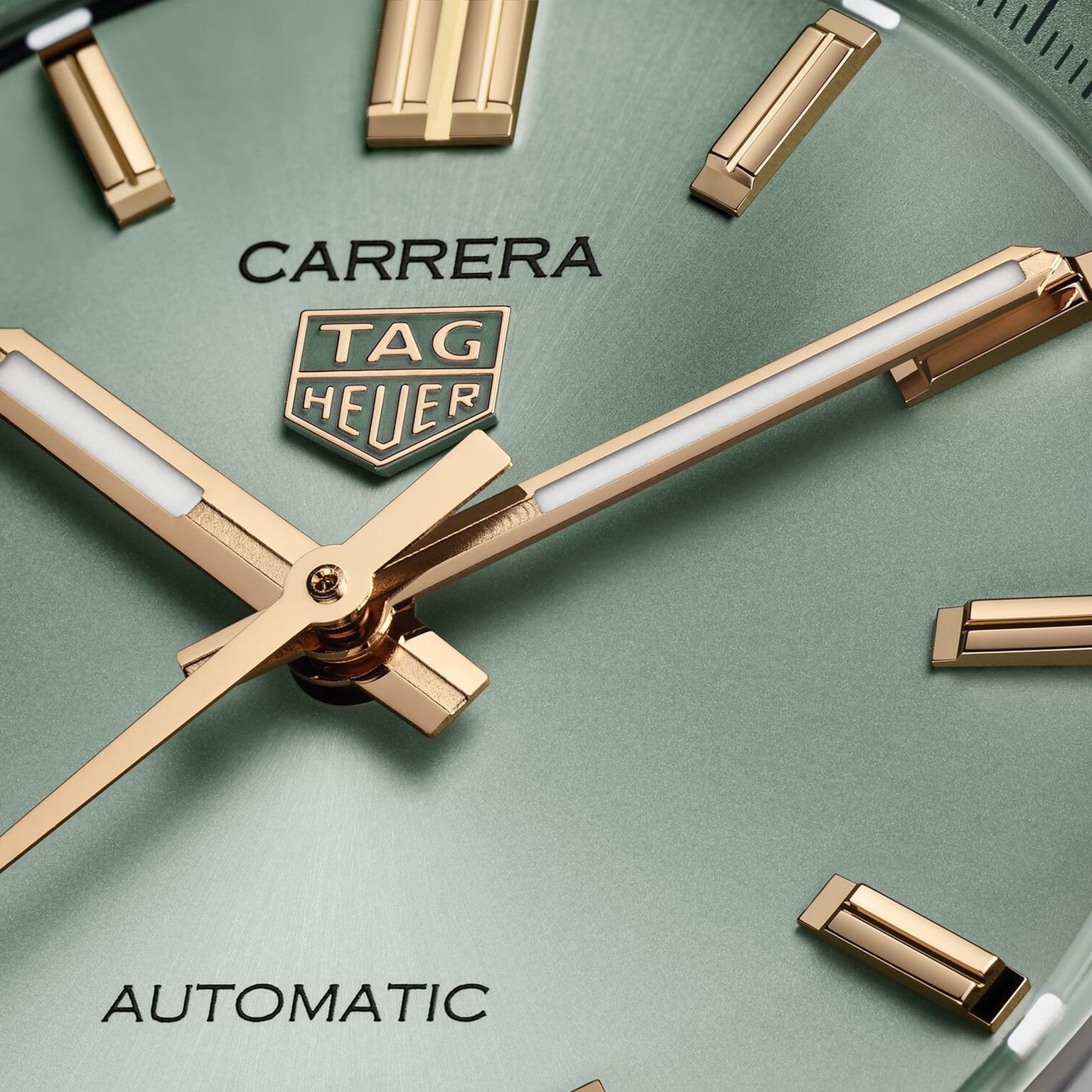 Close-up of the TAG Heuer Carrera Date watch face, featuring a green dial with gold hour markers and hands, showcasing the elegance and endurance of this iconic TAG Heuer timepiece.