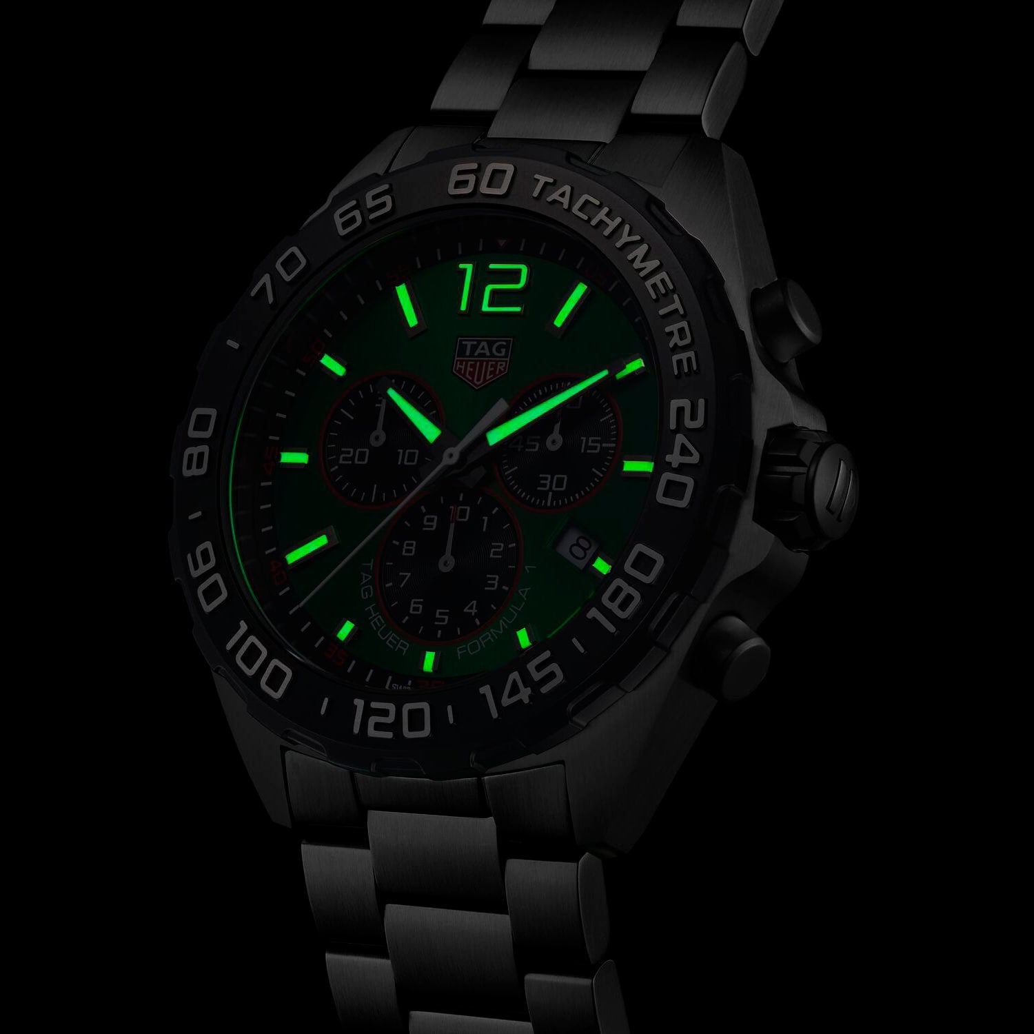A TAG Heuer Formula 1 Chronograph wristwatch features a black design with green illuminated numbers and hour markers for clear time display in the dark.