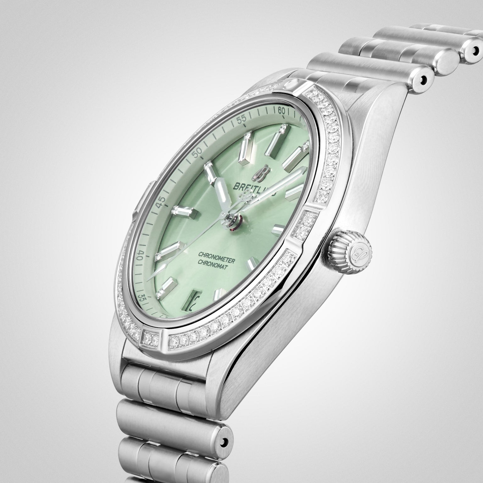 A Breitling Chronomat Automatic 36 wristwatch in silver with a mint green dial, diamond-set bezel, date display, and signature Rouleaux bracelet, angled against a light background.