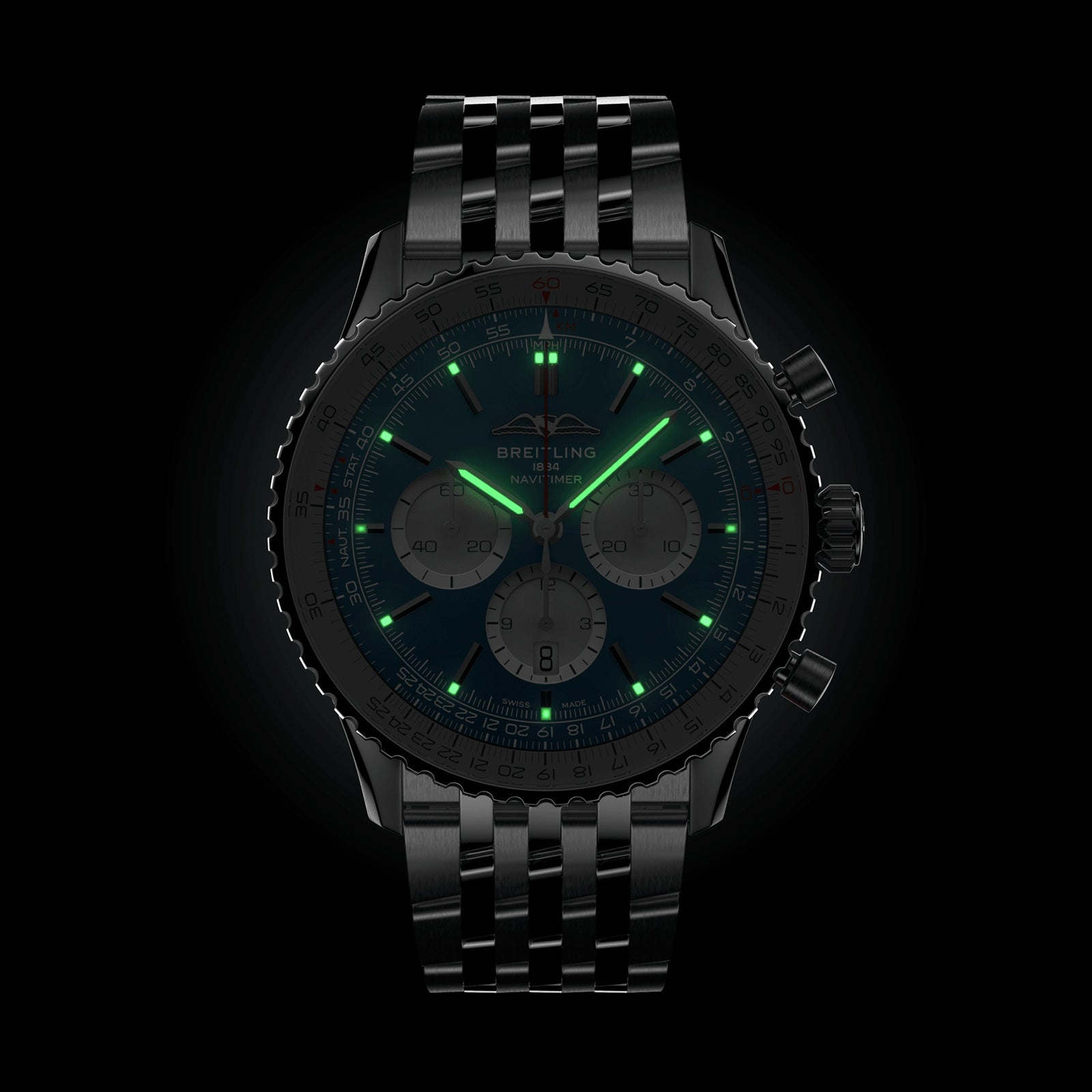 A Breitling Navitimer B01 Chronograph 46 wristwatch with a black dial and metal bracelet is shown in the dark, featuring glowing green luminescent hands and hour markers.