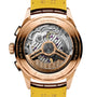 Close-up of the Breitling Premier B01 Chronograph 42’s back, featuring an 18K red gold case, visible COSC-certified movement, engraved details, and a yellow leather strap.