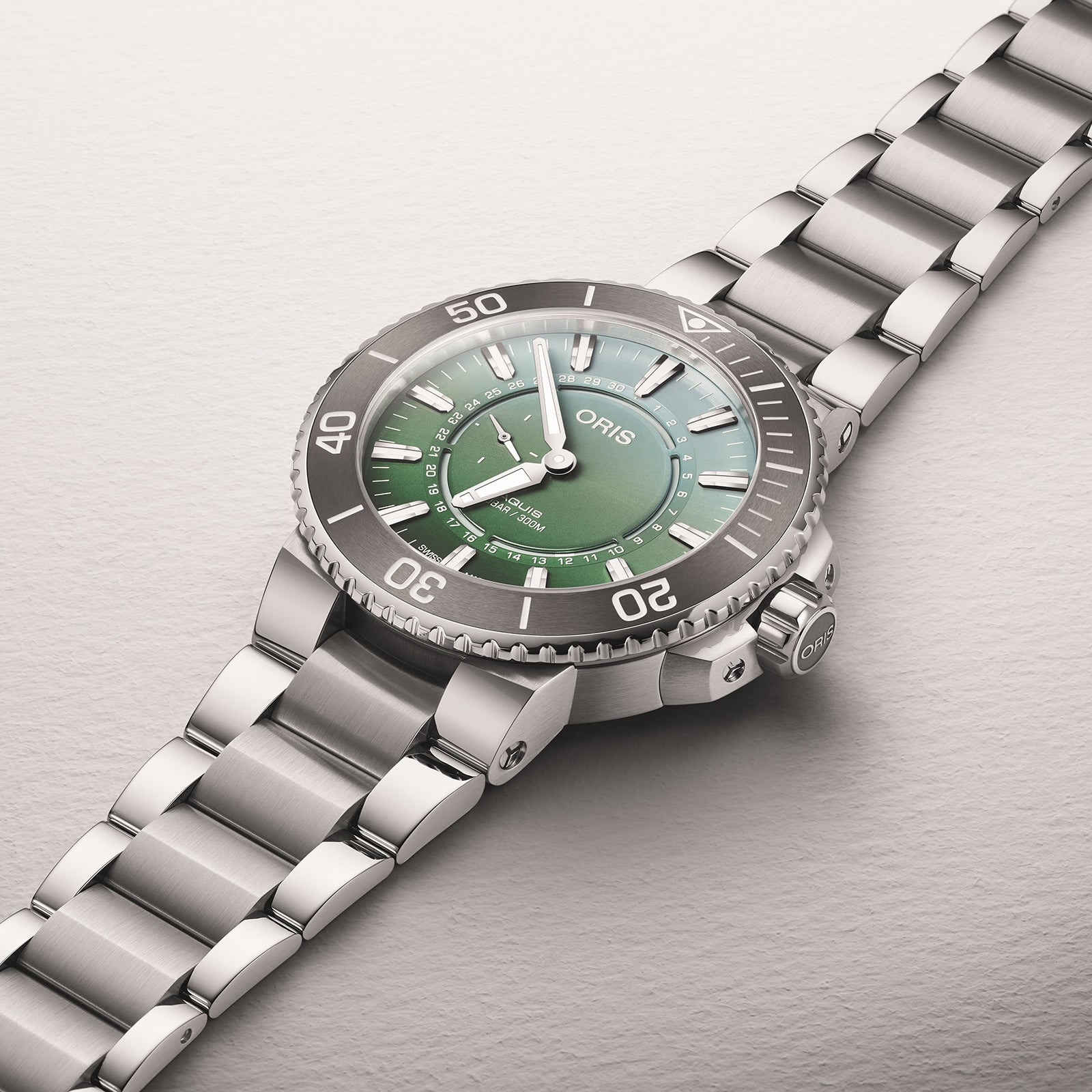The Oris Dat Watt Limited Edition II is a stainless steel watch with a green dial, silver hour markers, and a metal link bracelet, inspired by Wadden Sea conservation, shown against a light background.