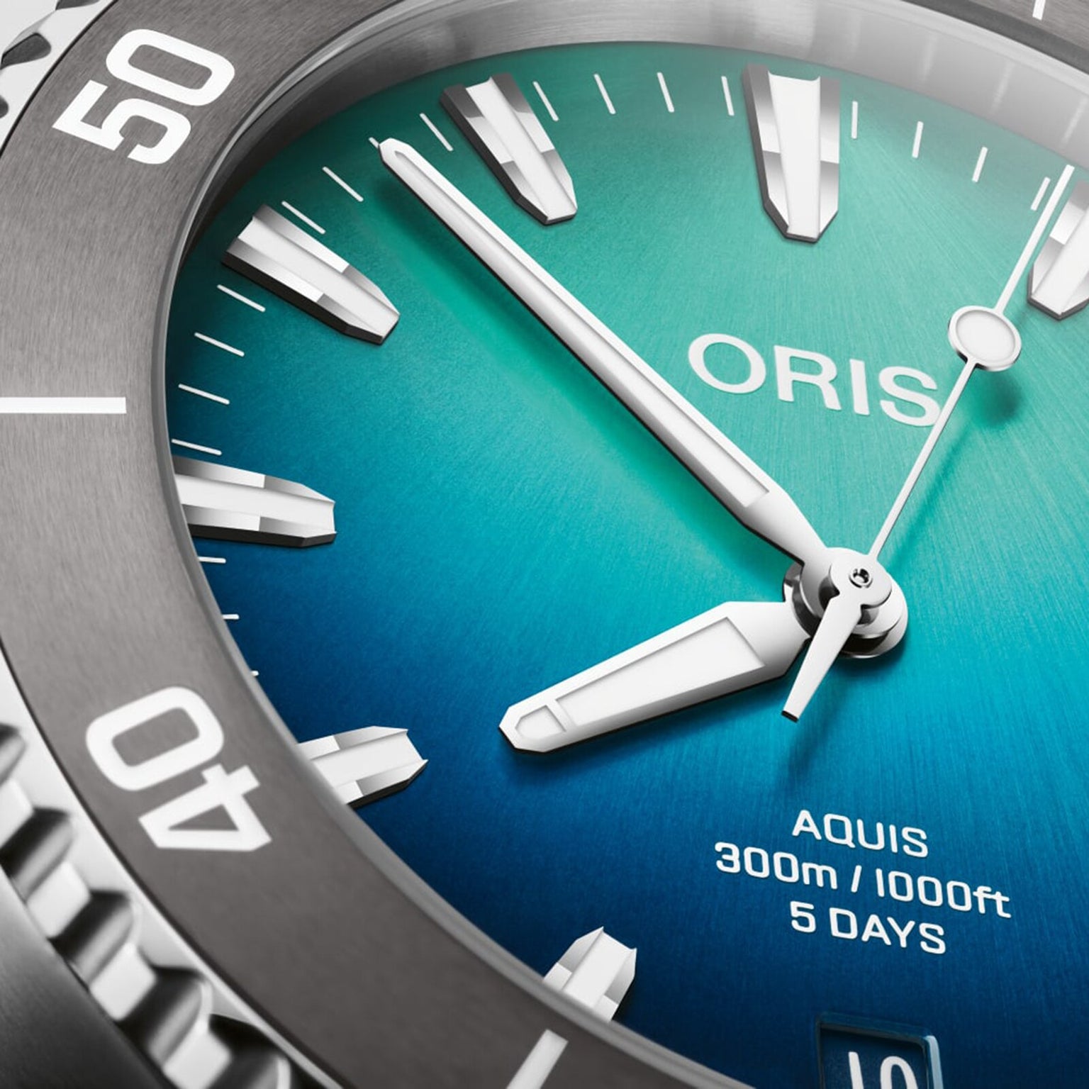 Close-up of the Oris Great Barrier Reef Limited Edition IV watch face featuring silver hour markers, a blue-green gradient dial inspired by the reef, and Aquis 300m/1000ft 5 days text.