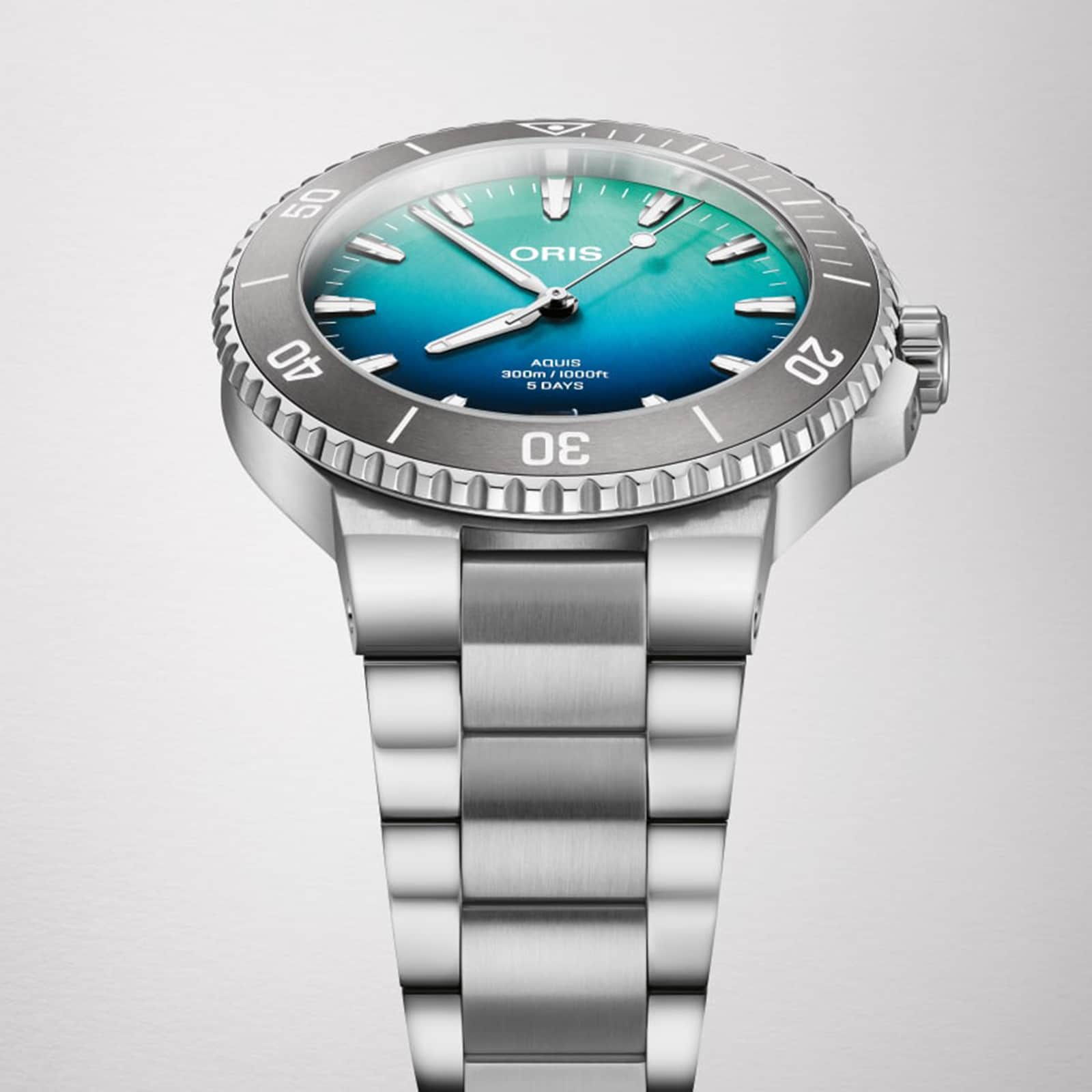The Oris Great Barrier Reef Limited Edition IV is a stainless steel automatic watch with a turquoise gradient dial, bold markers, and a silver rotating bezel, showcased against a plain white background.