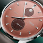 Oris watch with coral dial, silver baton markers, moonphase complication at 3 o'clock, and date window at 6 o'clock.