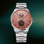 Silver stainless steel watch with rose dial, moonphase subdial, date window, and three hands on metal bracelet.