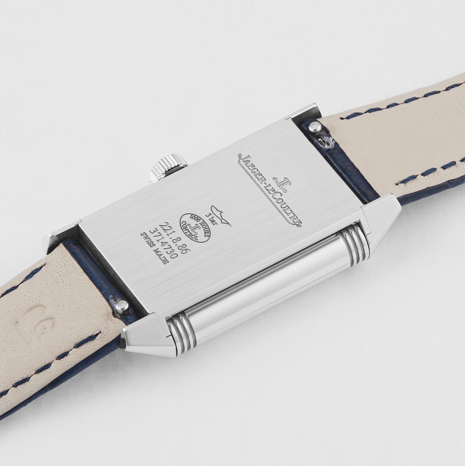 A close-up of the back of the Jaeger-LeCoultre Reverso Classic Small showcases its rectangular stainless steel case and beige leather strap, featuring engraved branding and reference numbers on this iconic timepiece.