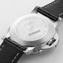 Close-up of the back of a Panerai Luminor Marina wristwatch, showing engraved details on the stainless steel case, black leather strap with white stitching, and a partially visible crown guard.