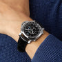 A person in a blue textured sweater wears a Panerai Luminor Chrono luxury sports watch with a black leather strap and detailed black dial on their left wrist.