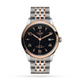 The TUDOR 1926 features a black textured dial, gold hour markers, date display, and a two-tone silver and gold bracelet—a refined timepiece blending timeless style with TUDOR’s renowned precision.