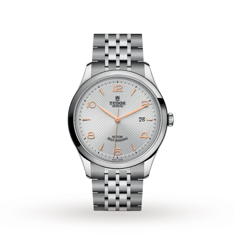 The TUDOR 1926 is a silver wristwatch featuring a textured white dial, gold hour markers, date display at 3 o’clock, and a stainless steel bracelet—an elegant nod to classic mechanical timepieces.