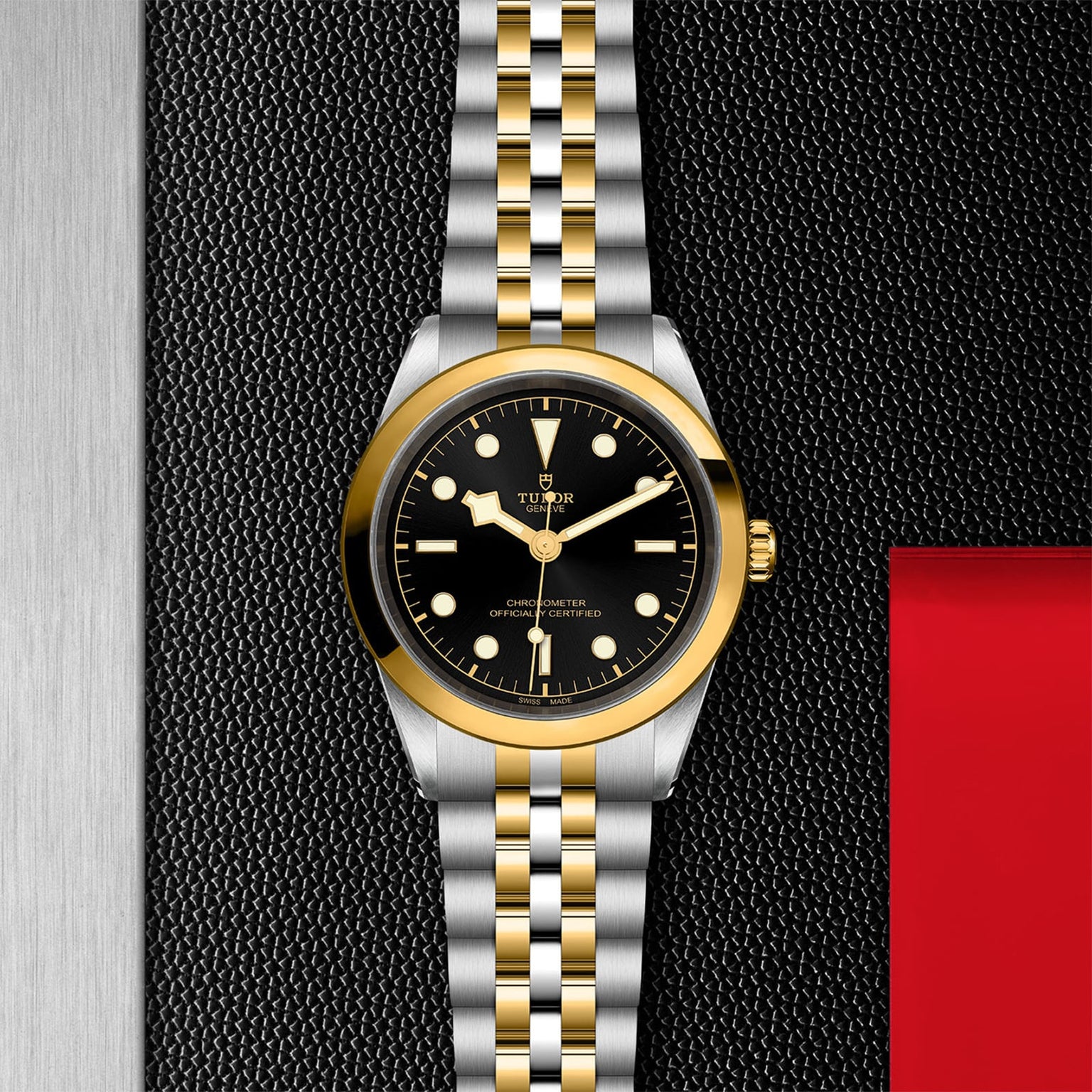 A TUDOR Black Bay One 41 S&G gold and silver wristwatch with a black dial displayed on a textured black background.