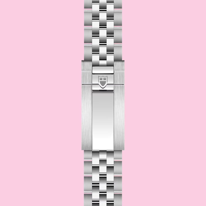 A stainless steel TUDOR bracelet with a polished clasp and embossed shield logo, shown vertically on a light pink background—ideal for pairing with the TUDOR Black Bay Chrono or any Swiss chronometer-certified watch.