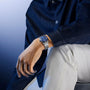 Steel watch with blue dial and rotating bezel on metal bracelet worn on wrist.