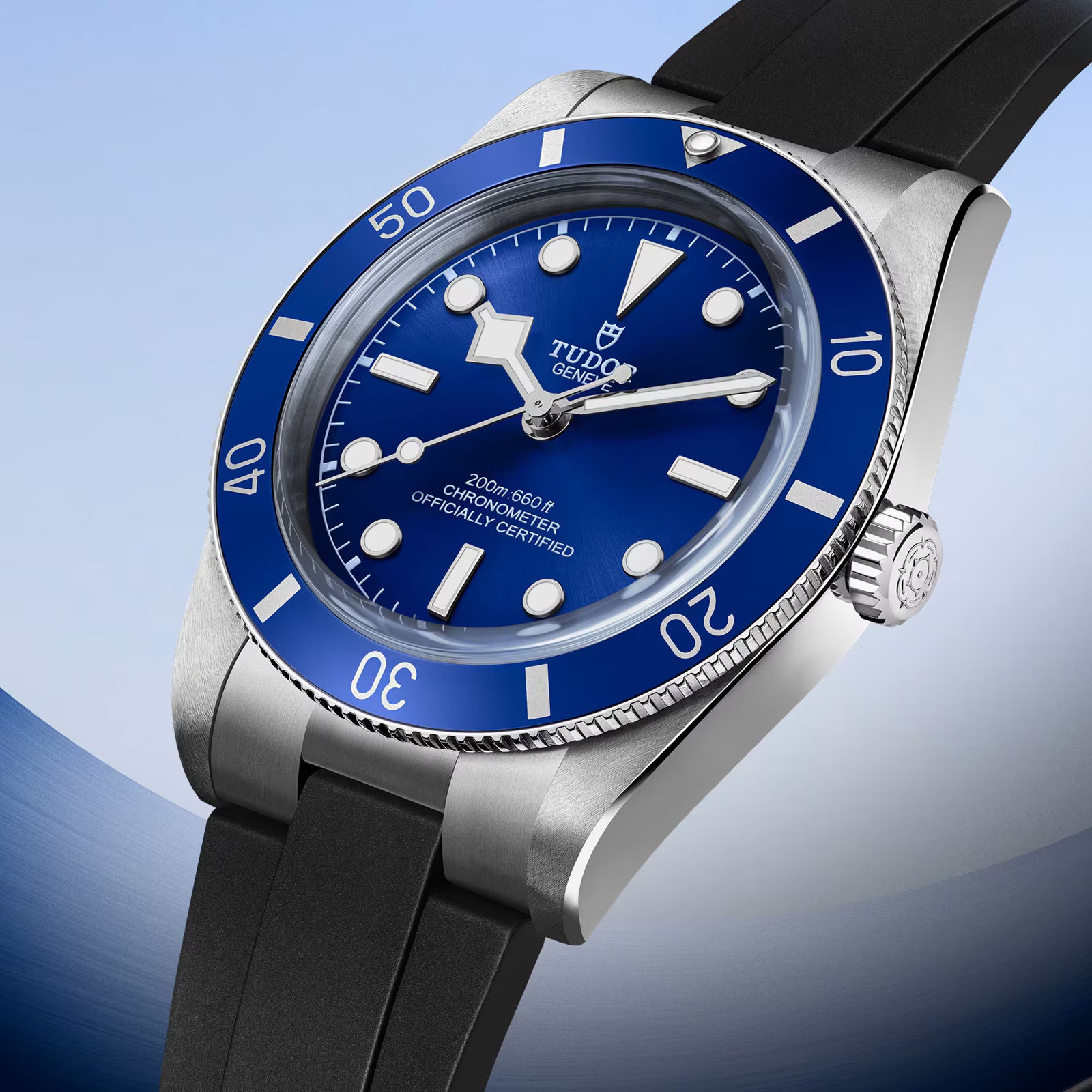 Tudor watch with stainless steel case, blue dial, blue rotating bezel, and black rubber strap.