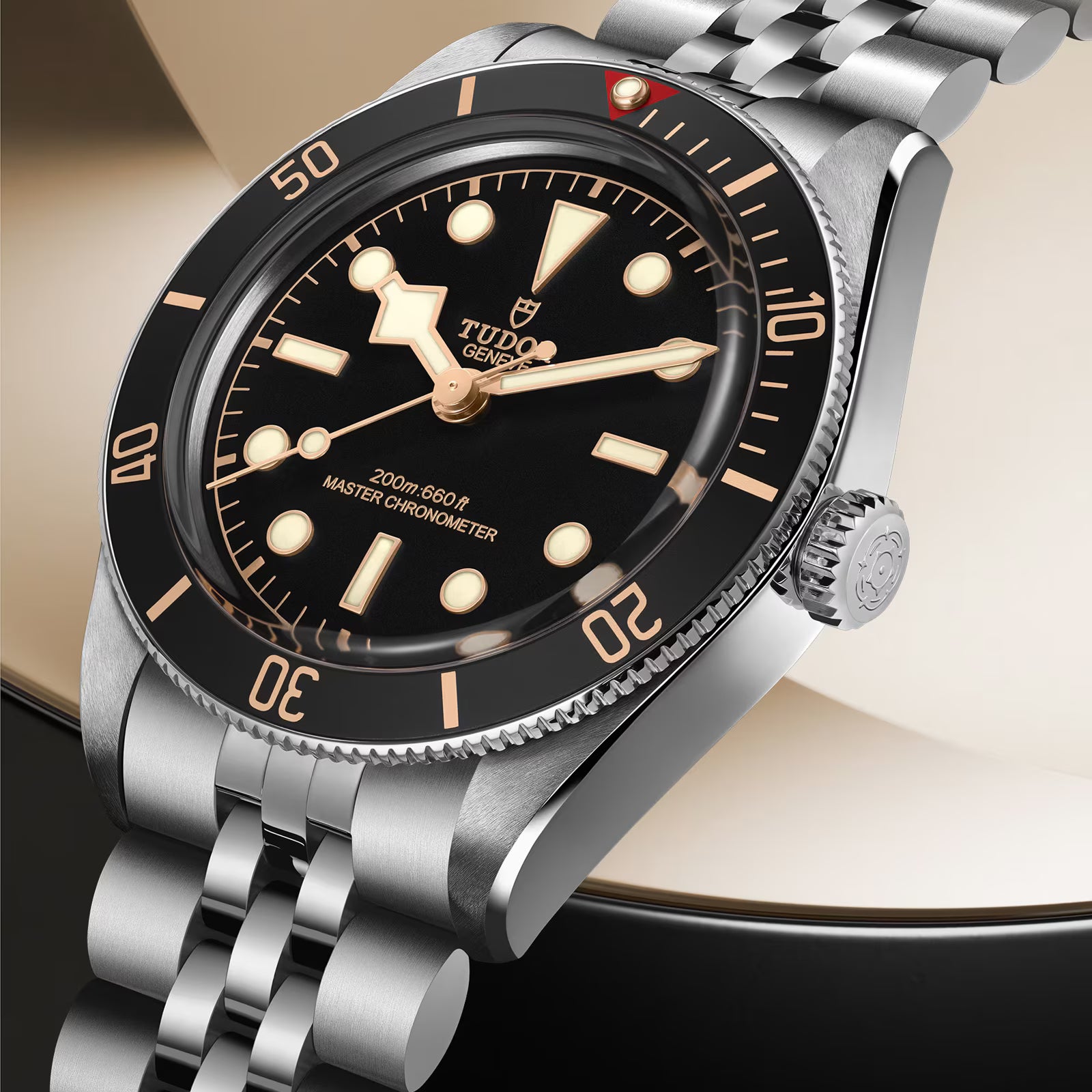 Tudor stainless steel watch with black dial, gold hour markers, rotating bezel, and matching metal bracelet.