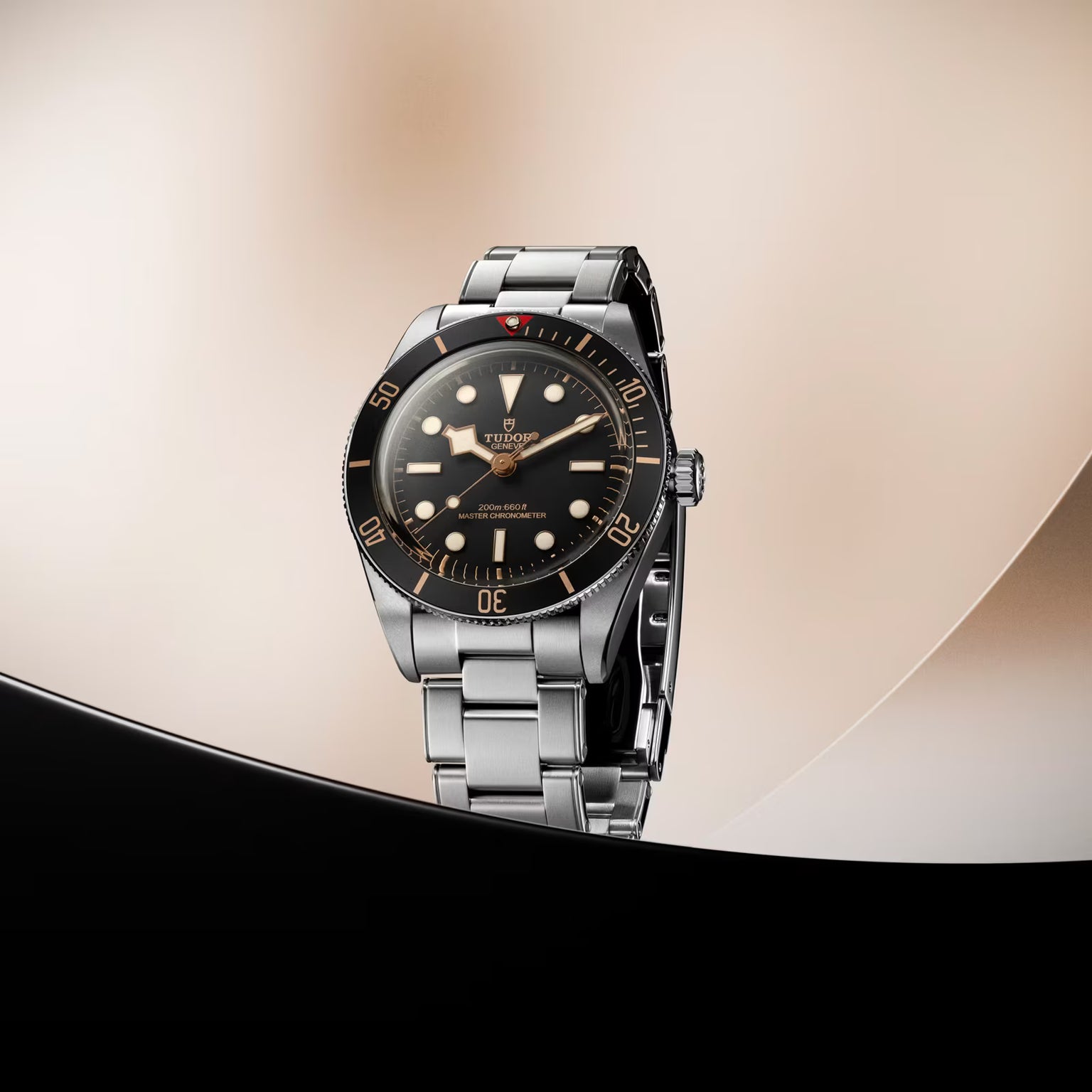 Steel dive watch with black dial, luminous hour markers, rotating bezel, and steel bracelet on neutral background.
