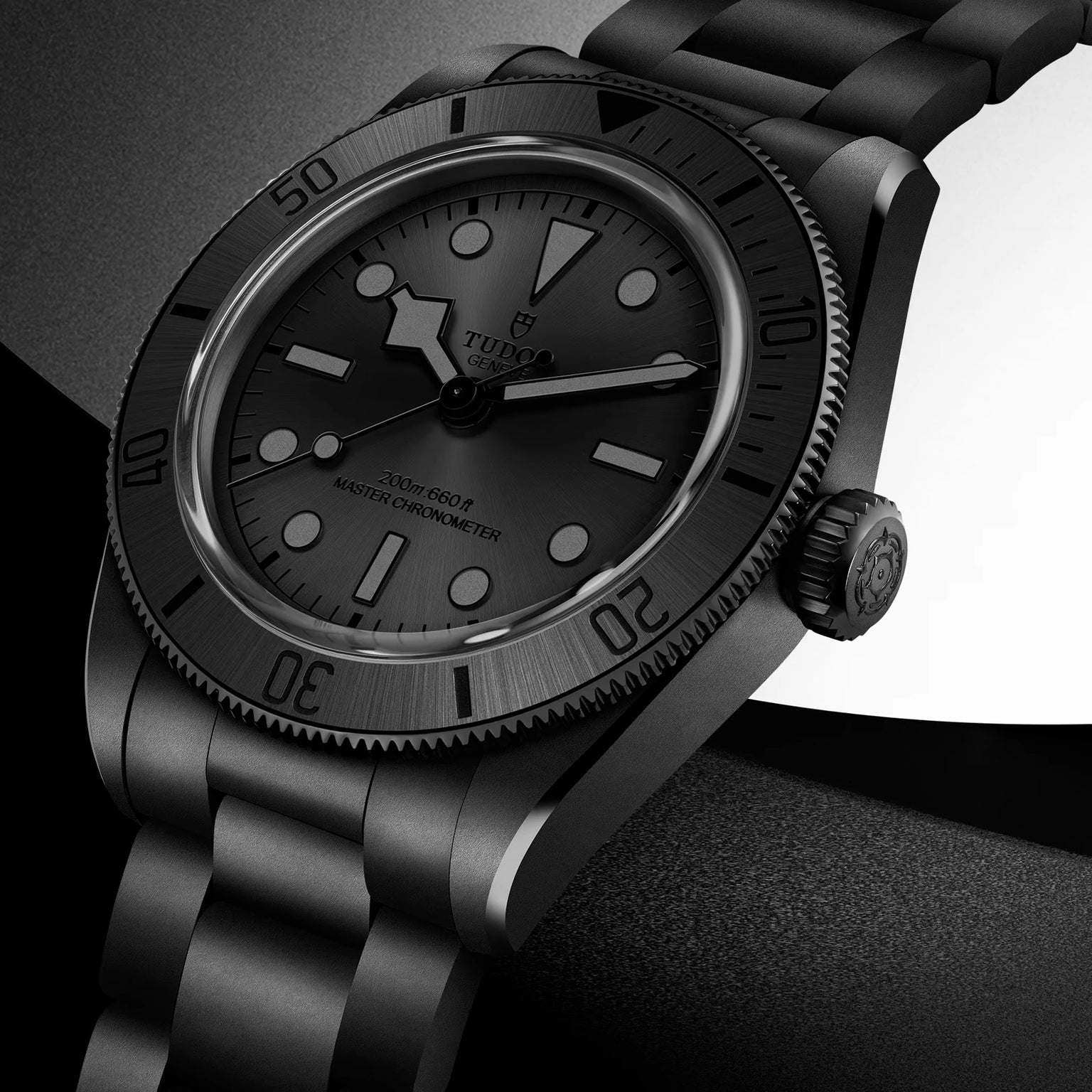 Black dive watch with ceramic bezel, black dial, round indices, and matching black metal bracelet displayed at an angle.