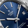 TUDOR watch with blue dial, silver hour markers, white hands, date window showing "28", and "CHRONOMETER OFFICIALLY CERTIFIED