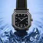 The Gerald Charles Maestro 2.0 Ultra-Thin watch, featuring a black strap and dial, is elegantly displayed against a rippling blue water background.
