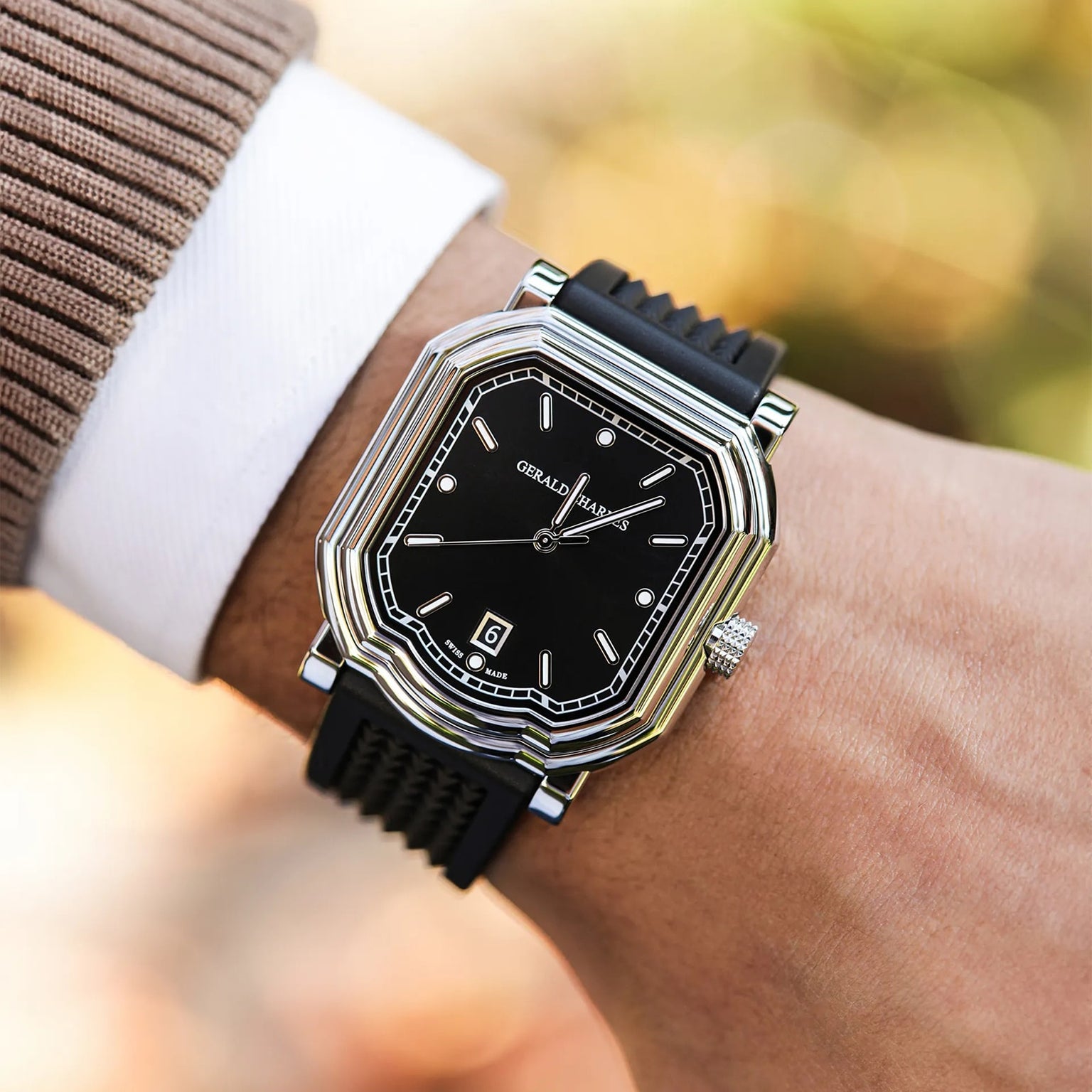 A person wears a black, rectangular Gerald Charles Maestro 2.0 Ultra-Thin wristwatch with a black strap on their left wrist.