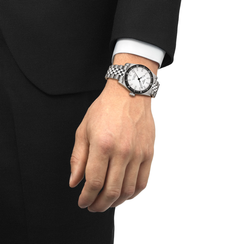 Hand wearing a silver wristwatch with a black face on a white background