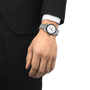 Hand wearing a silver wristwatch with a black face on a white background